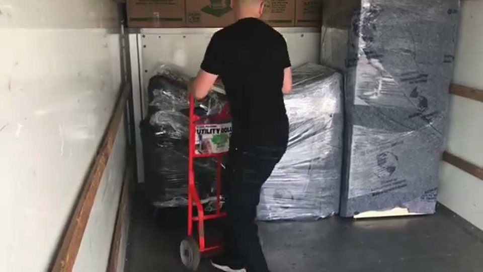 man moving a salon shampoo backwash unit across a salon floor